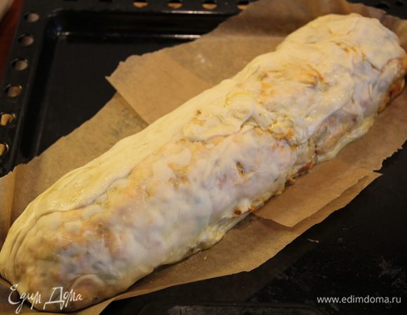 Тем временем раскатать тесто в прямоугольник так, чтобы можно было полностью завернуть наш рулет. В книге было указано "до 200гр готового бездрожжевого слоеного теста". Не знаю, на мой взгляд, можно и больше теста брать =) Кстати, под тесто тоже подложите бумагу для выпечки. Достаем приготовленный рулет из духовки и кладем его на тесто, заворачиваем полностью. И вот тут-то у меня снова начались проблемы: мало того, что тесто рвалось из-за того, что было очень тонким, и оно размокало и плавилось от горячего рулета, так когда я все же завернула все, поставив заплатки на дырках .. я поняла, что рулет прилип ко столу)))) Всеми правдами и неправдами мне удалось поддеть его пластиковой разделочной доской и перенести на бумагу, а затем на противень. Так что лучше сразу под тесто подложить либо большую пластиковую разделочную доску, либо бумагу для выпечки, вместе с которой вы и отправите рулет в духовку. Смазать его оставшейся половинкой желтка и поставить минут на 10 на 200°С (смотрите по готовности теста).