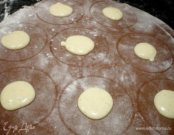 Размечаем на одной части теста круги при помощи стакана. Выкладываем в центр начинку, смазываем края желтком и кладем второй пласт теста.