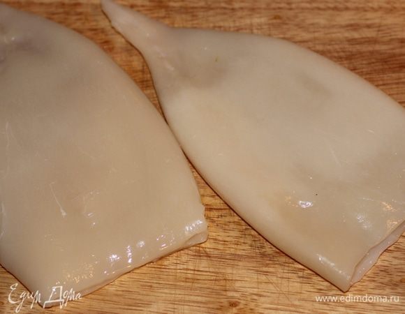 Тушки кальмаров очистить от тонкой внешней пленки, аккуратно поддевая ее пальцами и стараясь не порвать - целиком она легче снимается. Промыть водой, тщательно обсушить бумажными салфетками.