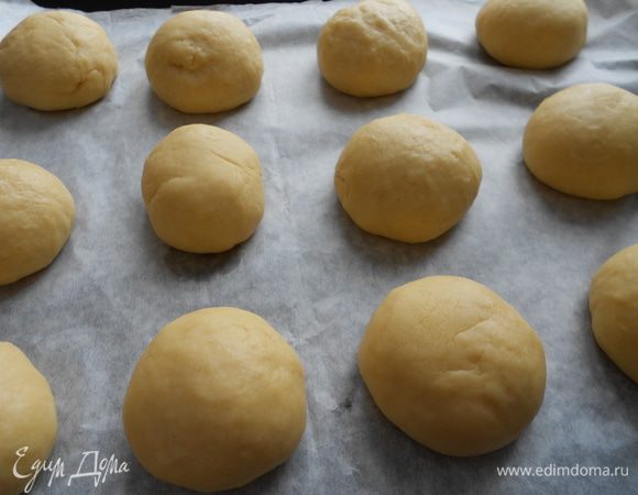Разделите тесто на 12 равных частей, скатайте ровные шарики, выкладывайте на противень, застеленный пекарской бумагой. Дайте время булочкам подойти, около 30 минут.