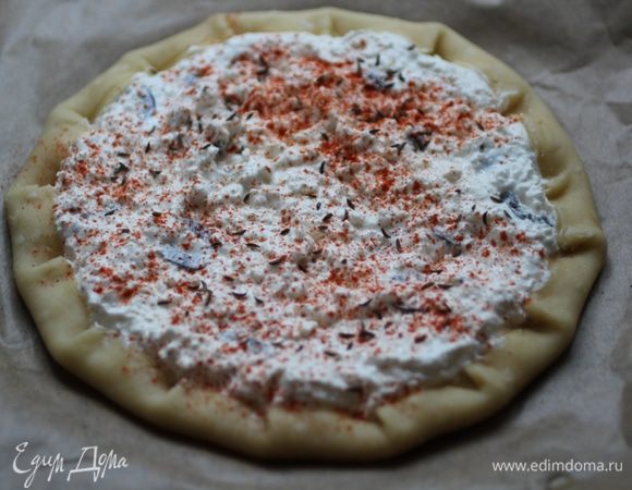 Положить корж на застеленный пергаментом противень, выложить на него начинку и защипнуть края. Посыпать тмином и паприкой.