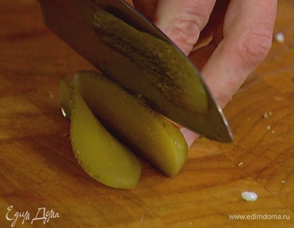 Соленый огурец нарезать тонкими ломтиками.