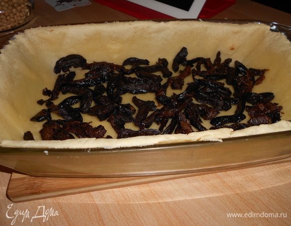 Убираем с коржа груз, нарезаем чернослив, выкладываем на песочную основу, посыпаем сахаром и выливаем тыквенную смесь