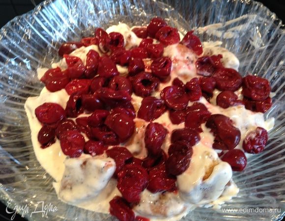 Емкость сферической формы выстелить пищевой пленкой. Выложить часть пряников в креме, сверху выложить часть вишен...