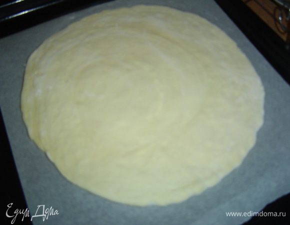 Достаем тесто из холодильника, каждый пласт раскатываем до толщины 3 мм, но один пласт должен быть больше на пару см в диаметре, меньший переносим на противень, застеленный пергаментом.