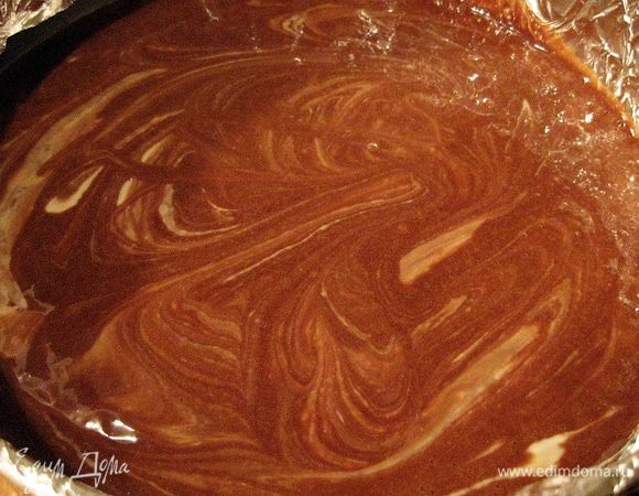 Выкладываем половину шоколадной массы в форму. Затем всю творожную массу распределяем по шоколадной поверхности. И выкладываем остаток шоколадной массы.
Слегка перемешиваем черенком ложки два верхних слоя.
