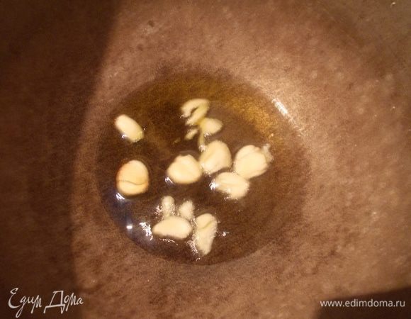 В казан с толстым дном вылить масло и добавить раздавленные дольки чеснока.
