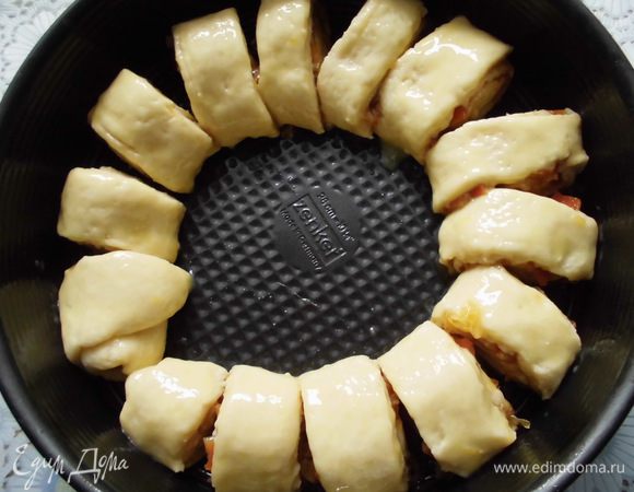 Аккуратно свернуть тесто в рулет и нарезать его на 14 кусочков. Форму (у меня 26 см, но можно и 24) смазать растительным маслом и выложить кольцом рулетики. Смазать их желтком буквально с каплей молока и выпекать 30-40 минут. 