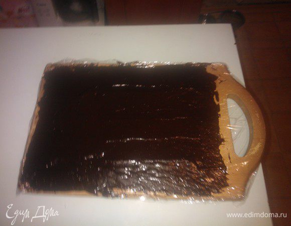 ... При помощи лопатки равномерно размазываем ее в прямоугольный пласт на всю поверхность доски. Даем подзастыть.... 
За это время мы успеем отмыть посуду, в которой растапливали черный шоколад, и приготовить белый слой...