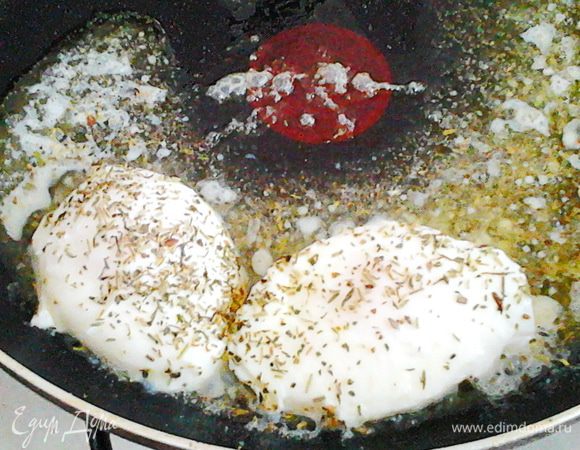 Посыпьте яйца травкой, полейте сверху маслом и дайте несколько минут хорошо прогреться.