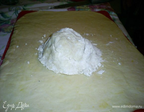 Когда тесто подойдет, раскатываем его в прямоугольный пласт толщиной около сантиметра, на его средину выкладываем комок из масляной крошки. 