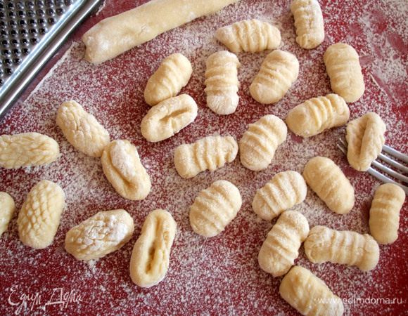 Прокатать каждый кусочек по ребрам вилки (по их вогнутой стороне), чтобы образовались характерные для ньокки бороздки. Можно прокатывать по обратной стороне мелкой терки. Дать ньокки отдохнуть около 15 минут. 
