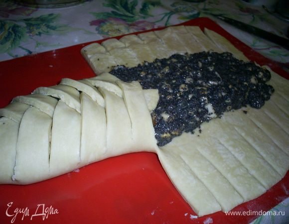 Теперь полоски теста выкладываем на начинку по одной с каждой стороны пласта, заплетая косичку.