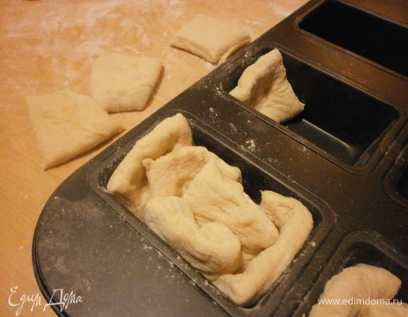 Нарезать острым ножом на прямоугольники, размером приблизительно 6 см. на 9 см.Укладывать вертикально по 5 прямоугольников в каждую формочку и не очень плотно. Накрыть и дать подойти в тёплом месте, пока булочки не увеличатся вдвое.