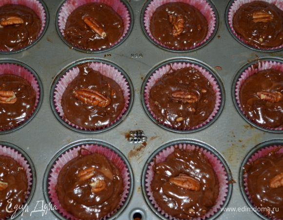 В большой чаше смешать яйца и сахар. Добавить муку, какао и пищевую соду. 
Затем шоколад растопленный. Как все перемешалось, добавим оставшийся шоколад и рубленные орехи. Разложим массу по формочкам 3/4 часть, они поднимутся. Я украсила еще сверху крупным пеканом - половинкой. Поставить в духовку на 20 мин.