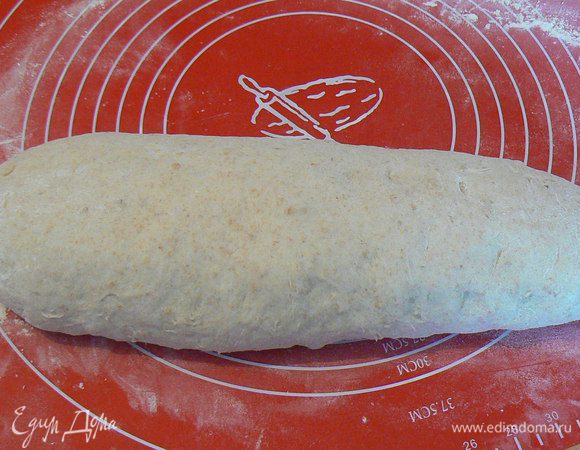 Потом придать хлебу овальную форму, смазать молоком и посыпать овсяными хлопьями. Накрыть плёнкой и поставить на расстойку еще на 30-40мин.