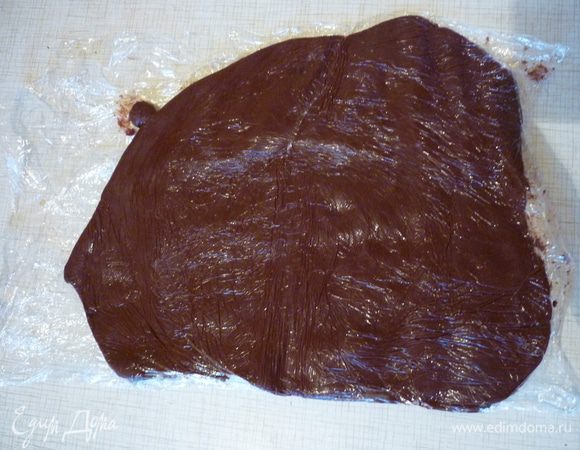 Остывшую шоколадную массу положить между двумя слоями полиэтиленовой плёнки и раздавить руками или раскатать скалкой в прямоугольник. Убрать до использования в холодильник.