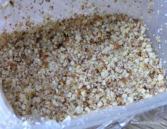 Прямоугольную форму (объемом около 800 мл) застелить пищевой пленкой, смазать маслом, выложить половину измельченной ореховой смеси, разровнять, немного придавливая,

