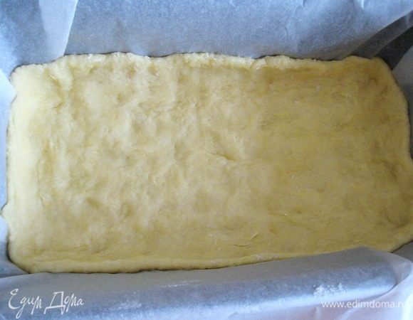 В форму, застеленную пекарской бумагой, выкладываем тесто и равномерно распределяем по всему дну, делая небольшие бортики. (В этот раз я использовал прямоугольную форму 24х13 см, но можно взять и обычную, разъёмную на 20 см.)