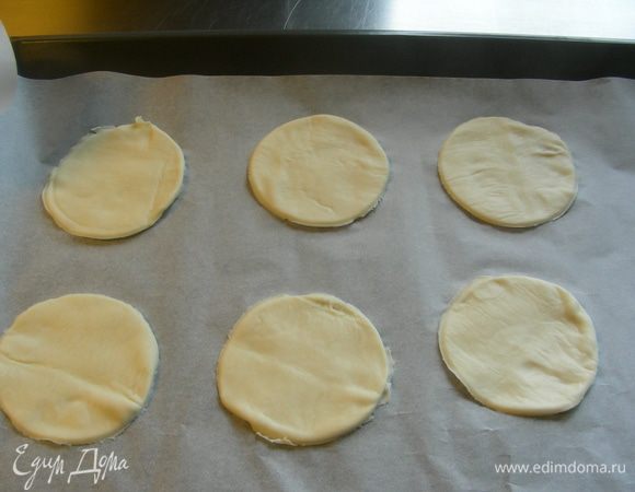 Песочное тесто раскатываем тонко и вырезаем небольшие кружочки (например, стаканом). Выкладываем их на противень на бумагу для выпечки.
