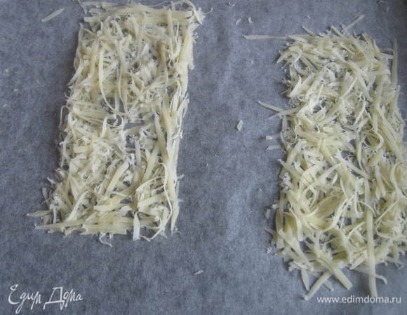 Застелить противень бумагой для выпекания. Натереть сыр на крупной терке, сформировав из него прямоугольники. Отправить в духовку, разогретую до 170°C, на 5 минут. Может потребоваться чуть меньше или больше времени.