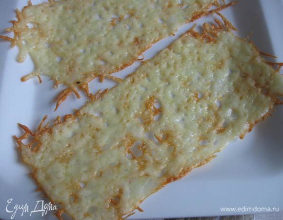 Достать сырные «чипсы» из духовки, дать остыть, отделить от бумаги, свернуть в рулончики, завернув для этого на некоторое время в бумагу. «Чипсы» послужат украшением для блюда.