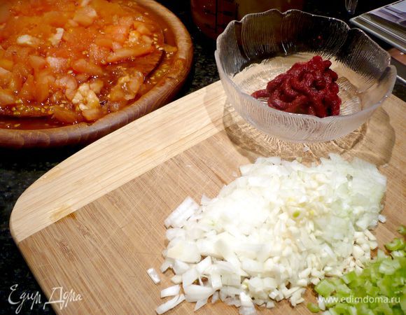 Готовим ингредиенты для соуса. У помидоров вырезаем место прикрепления плодоножки и надрезаем нижнюю часть крест-накрест, укладываем в кастрюлю с кипятком, буквально на одну минуту. Сельдерей, лук и чеснок мелко режем. С помидоров снимаем кожицу и режем на кусочки.
