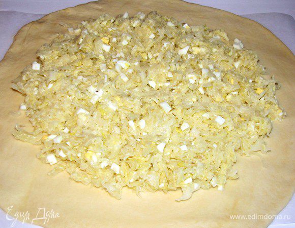  Отрежьте небольшой кусочек теста и отложите, оно понадобится нам для украшения. Остальное  тесто раскатайте в большой круг на пергаменте, смазанном маслом. На середину круга выложите начинку, оставляя довольно широкие края.