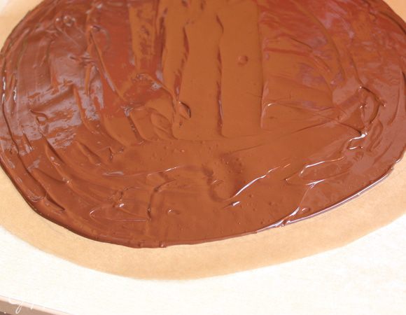 Делаем наше покрывало... Берем бумагу и вырезаем круг диаметром 35 см. Внутри его отступаем на 2 см от края, рисуем еще один круг. На всякий случай я приложила свой круг к торту, проверила подойдет или нет... немного замазав конечно его... Теперь разогреваем шоколад на водяной бане, шоколад беру темный, 55% какао. Выливаем шоколад на бумагу и размазываем не доходя 2 см до края. Даем ему  остыть на столе примерно минут 15.
