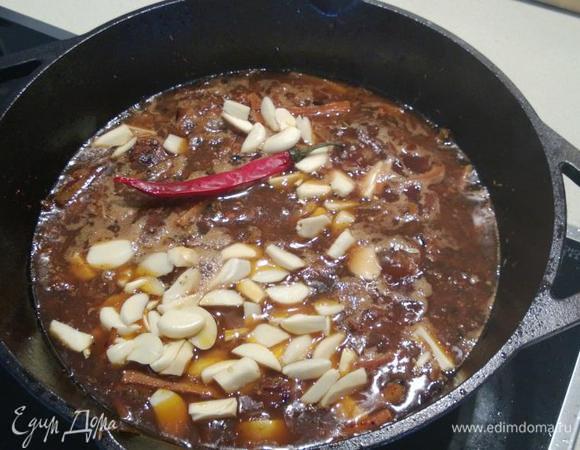 Теперь заливаем горячую воду (так, чтобы толщина воды над мясом получилась 1-2 см), добавляем чеснок.