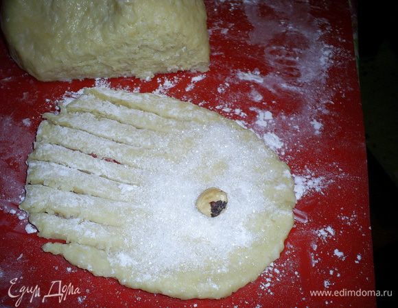 Далее оригинальный рецепт гласил: "сформируйте из теста палочки, выложите на противень и загните, придавая форму рогаликов". Мне это показалось совсем не интересно. Я раскатывала овалы с большим диаметром около 10 см. С одной стороны надрезала края, формируя полосочки. Половину овала посыпала чайной ложкой сахара и клала орешек.