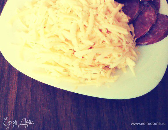 Колбасу нарезать кружочками. Сыр натереть.
