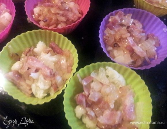 В формочки для запекания, у меня силиконовые выложить цветную капусту на нее обжаренный лук с беконом, 