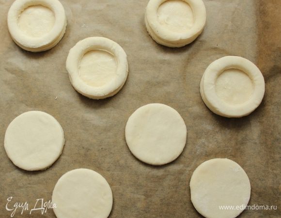 Получившиеся колечки из теста положить на 4 больших кружка, чтобы получились бортики. Поместить их и оставшиеся 4 больших кружка на противень, застеленный листом пергамента, присыпать тертым сыром и семенами кунжута, стараясь присыпать только края «сложных» кружков. Выпекать в разогретой до 200 ''С духовке 10-12 мин.