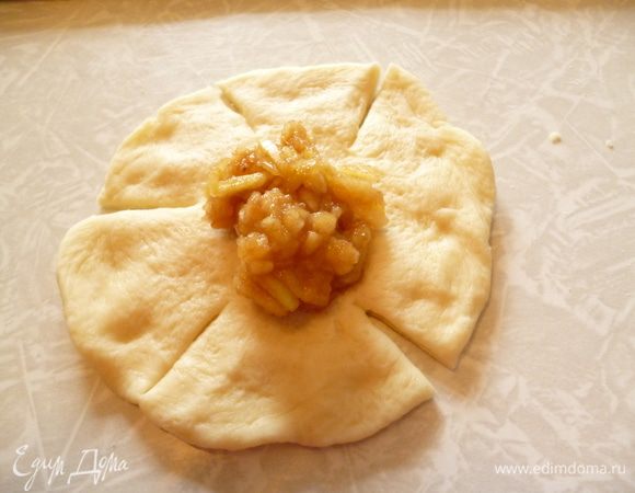 Берем одну часть теста и руками формуем из него лепешку толщиной около 0,5-1см. Вообще дрожжевое тесто не рекомендуется раскатывать скалкой,т.к.оно из-за этого утрачивает свою воздушность и поэтому мелкие изделия лучше формовать руками.На середину выкладываем начинку и делим ножом лепешку на 5 лепестков.(один лепесток сделать немного больше.)