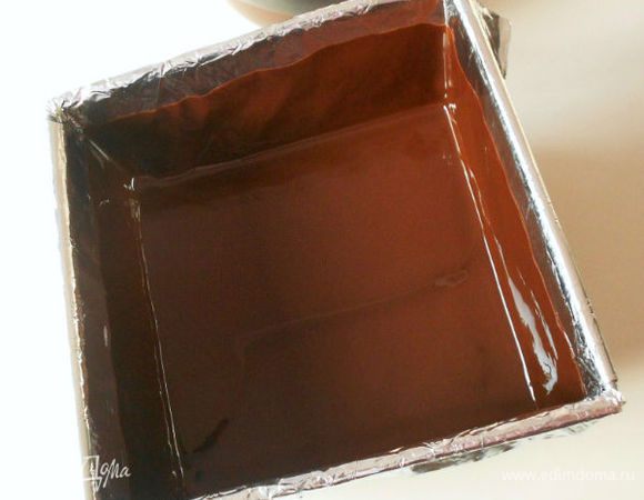 Поворачивая форму, распределить таким образом шоколад по остальным 3 бортикам. Поставить форму в морозильную камеру на 1 мин, затем ещё раз повертеть её, распределяя шоколад на бортики. Шоколадный слой по бокам должен быть достаточной толщины, иначе он в основном застынет на дне, а стенки будут хрупкими. Убрать форму в морозилку на 30 мин.