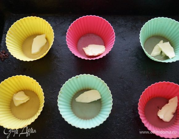 В силиконовые формочки положить по небольшому кусочку сливочного масла и поставить подогревать в горячую духовку, на минутку
