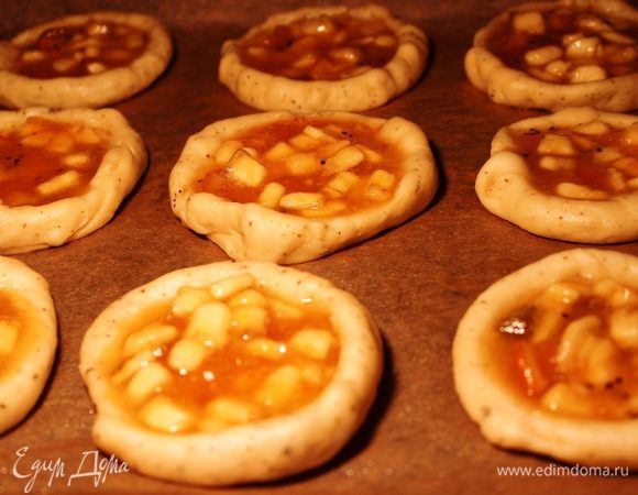 Духовой шкаф подогреть сначала до 100 градусов. Подготовить начинку: смешать все ингредиенты - бананы, джем и крахмал (бананы предварительно нарезать) и распределить ее по ватрушкам. Поставить противень в духовой шкаф и увеличить температуру до 180 градусов. Во время прогрева от 100 до 180 градусов ватрушки немного поднимутся. Выпекать минут 20 