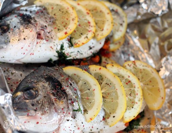 Рыбу чистим, моем, вытираем бумажным полотенцем. 
Мелко рубим зелень, режем кубиками морковь и болгарский перец. 
Рыбу натираем солью и смесью перцев, фаршируем смесью рубленной зелени и овощей. 
Укладываем слоями: лимоны, фаршированная рыба, лимоны. 
Кладем по кусочку масла на рыбу, поливаем вином. накрываем фольгой и отправляем в духовку на 10 минут при 200 градусах. 
Затем убираем фольгу, увеличиваем температуру и ждем появления золотистой корочки 3-5 минут. 