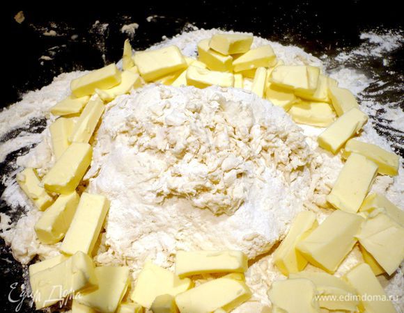 Высыпаем на рабочую поверхность горкой муку, делаем в ней углубление, наливаем в углубление в муке воду, выкладываем творог и перемешиваем хорошенько в центре воду и творог с мукой, затем выкладываем по краям кусочки масла.