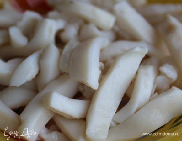 Тушки кальмаров очистить от тонкой внешней пленки, аккуратно поддевая ее пальцами и стараясь не порвать - целиком она легче снимается.  Нарезать соломкой. Опустить в кипящую воду, довести до кипения, снять с огня. Воду слить и промыть кальмар холодной водой. 