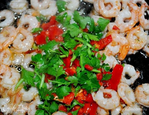 В сковороде разогреть оливковое масло, зубчик чеснока раздавить плоскостью ножа,обжарить его с двух сторон до коричневого цвета,чеснок удалить,добавить креветок,жарить помешивая 2 минуты, затем добавить нарубленные мелко петрушку и чили.