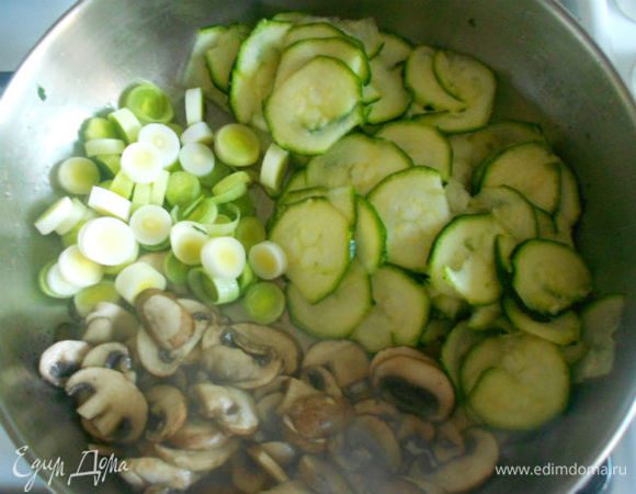 Сдвинуть грибы в сторону и обжарить до мягкости  нарезанный колечками (шайбами) порей и  натёртый на тёрке кружочками цукини. 
