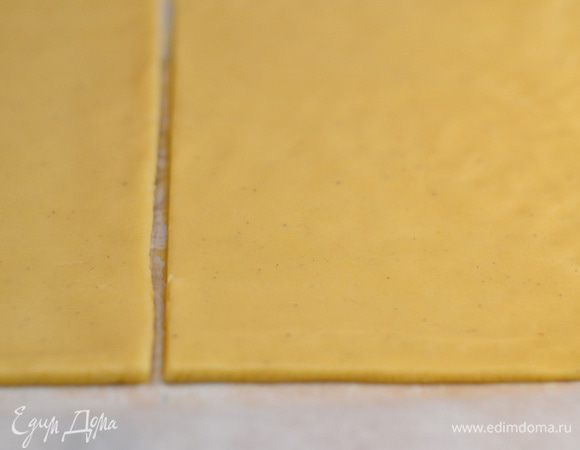 Достаем тесто из холодильника и раскатываем прямо же на пекарской бумаге его в один большой прямоугольник, затем делим его ножом на 2 равных части. Переносим на противень.