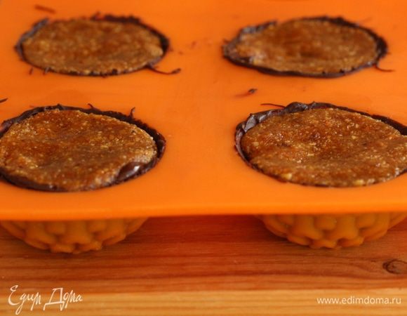 Достать форму из камеры, нанести еще один слой шоколада и охладить еще 5 минут. Положить в каждую ячейку  формы  по 1 кофейной ложке начинки. Немного утрамбовать. Сверху аккуратно залить оставшимся растопленным шоколадом. Убрать  обратно в морозилку до полного застывания примерно на 1 час.  