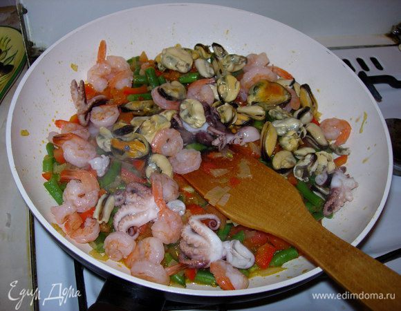 Когда лук, с перцем, фасолью и томатом поджарились, можно добавлять мидии, хвосты креветок, осьминожки и рис. Необходимо все тщательно смешать.