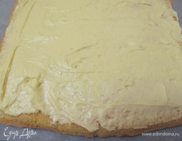 Покрыть бисквит кремом,оставив пару ложек для обмазки. Покрывать кремом  утолщая слой с одной стороны, эта сторона будет затем серединой рулета.