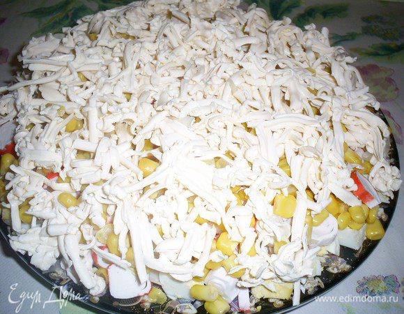 Теперь пришел черед делать наш салат кучерявым. Натираем на крупной терке плавленный сыр. Если он у вас достаточно мягкий и натираться ну никак не хочет, заранее положите его в морозилку, чтоб он немного затвердел.