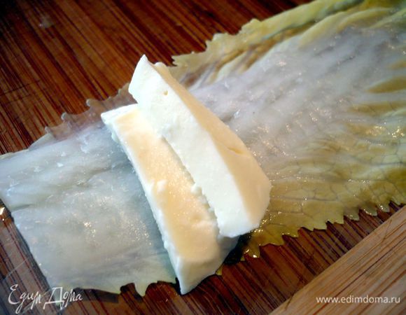 Разогреваем духовку до 180 градусов. Заворачиваем в каждый лист капусты по кусочку моцареллы. Смазываем форму для запекания сливочным маслом. 