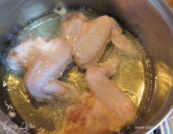 В сковороду налить масло и нагреть. Затем, при помощи щипцов положить крылышки в горячее масло. 